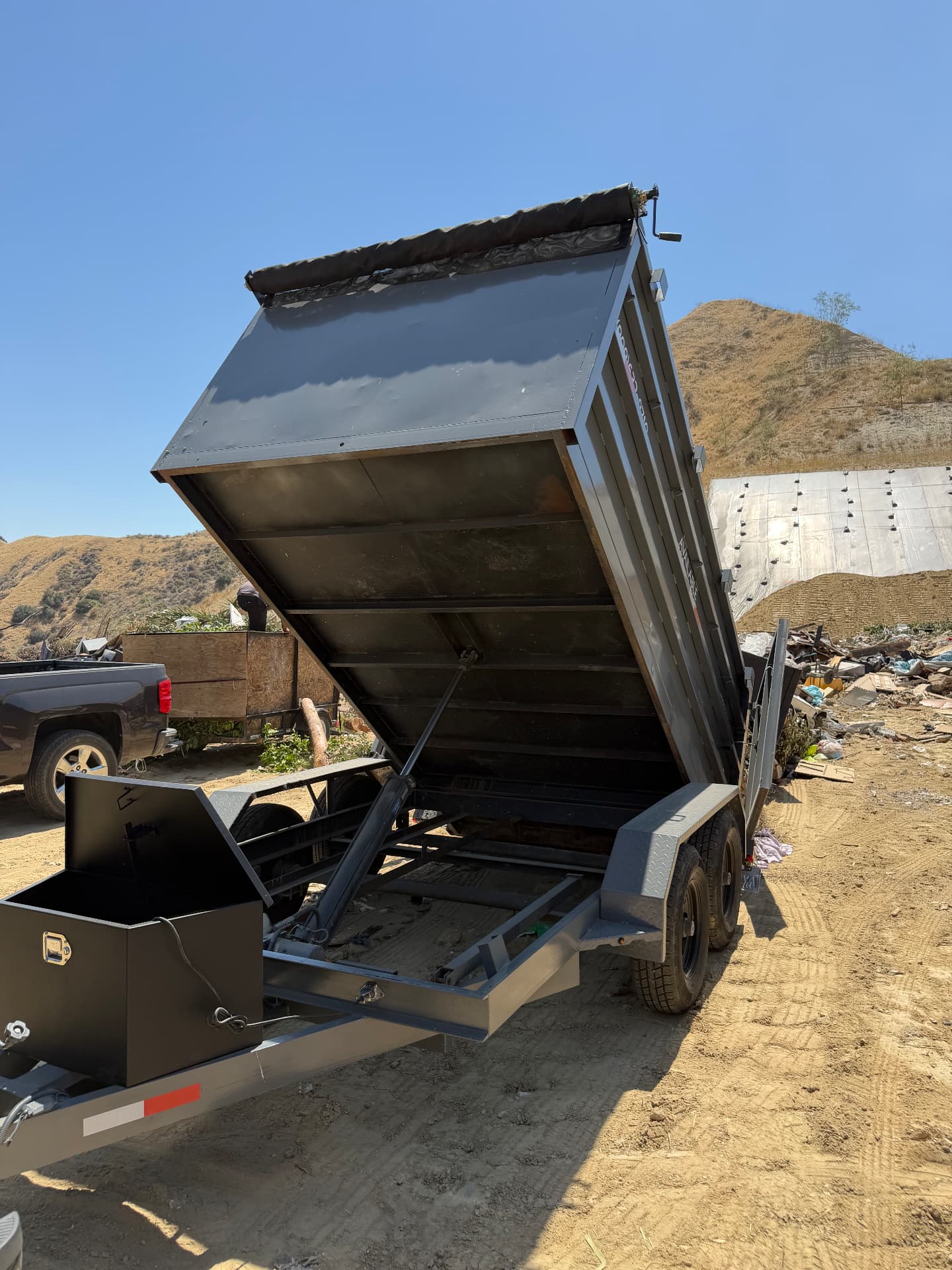 12ft dump trailer unloading debris at a dump site